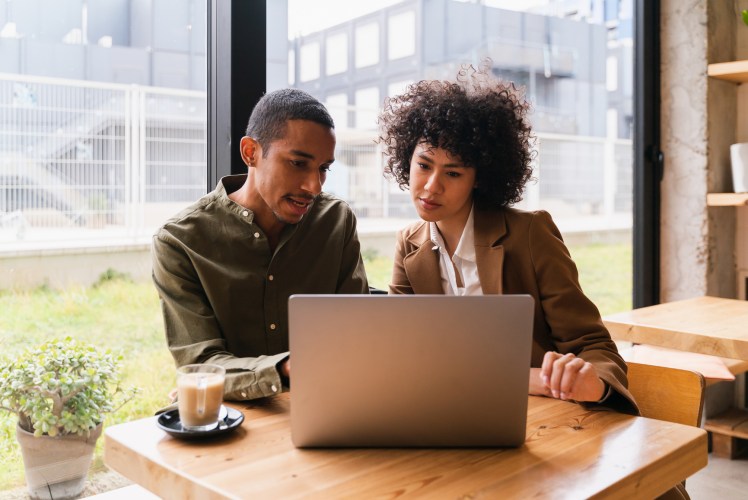 Two people discussing findings of AI-powered CRM research in front of computer.