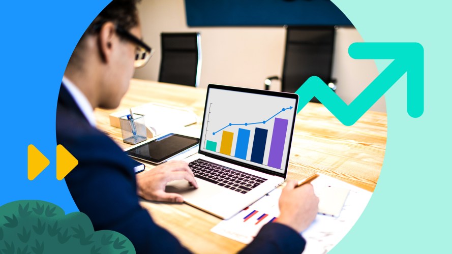 A salesperson views charts on his laptop and paper to calculate sales turnover.