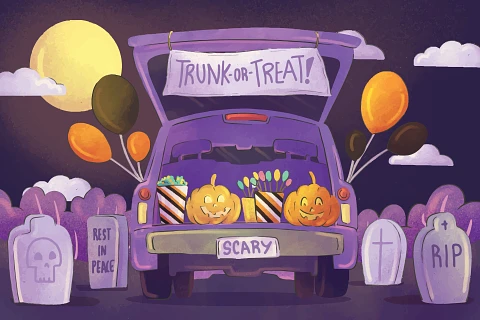 A car parked in a graveyard has it's trunk open and filled with pumpkins and treats for a trunk-or-treat event.