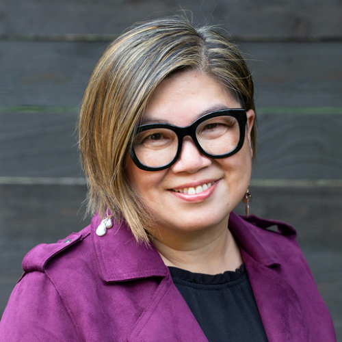 Hsiao-Ching Chou wearing dark rimmed glasses and a purple coat.