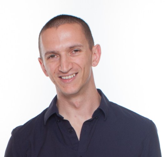 Headshot of Ben Risher white background. Ben white male wearing blue button up shirt.