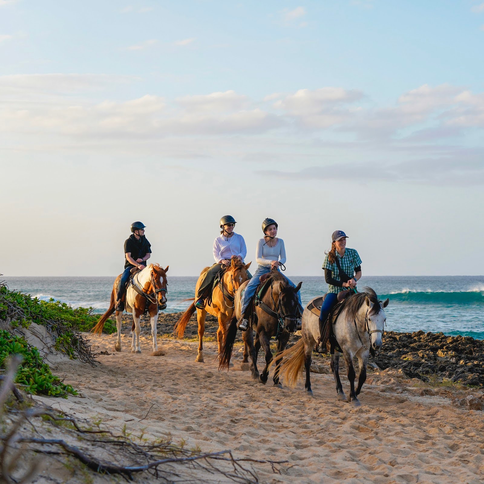 4 people horseback riding on the beach 