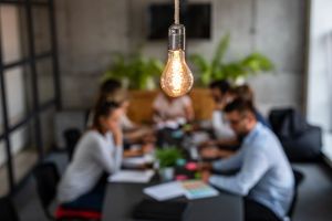 Jovens empresários estão discutindo juntos um novo projeto de inicialização. Uma lâmpada brilhante como uma nova ideia.