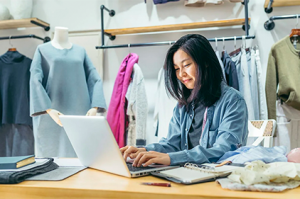 Eine Frau sitzt vor einen Laptop in einem Modegeschäft