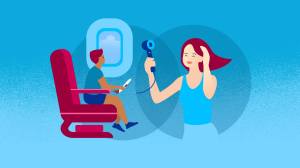 A man sitting in a seat of a airplane holding a toy airplane in his hand. A woman hair drying.