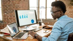 Male office worker, sitting at a desk, exploring the latest customer service trends on his laptop