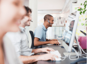 Tres personas frente a computadores atendiendo a los clientes a través de llamadas.