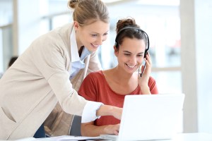 Dos mujeres interaccionando frente a una computadora.