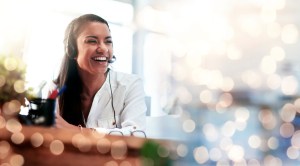 Mujer feliz, centro de llamadas y riéndose de fondo bokeh en servicio al cliente o telemercadeo en la oficina. Una mujer amigable, consultora o agente sonríe en consejos en línea o bromas divertidas en el lugar de trabajo