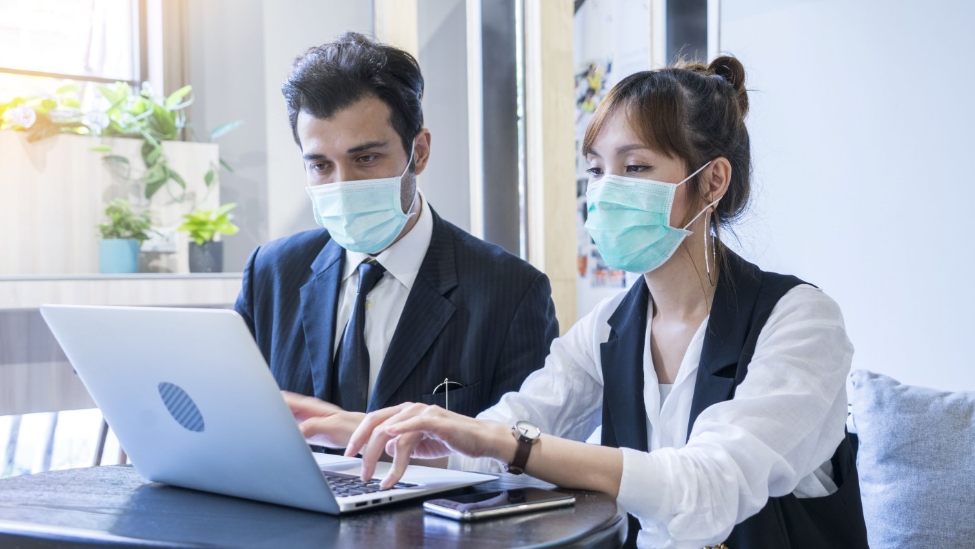 2 workers meeting together with laptop and wear protective masks